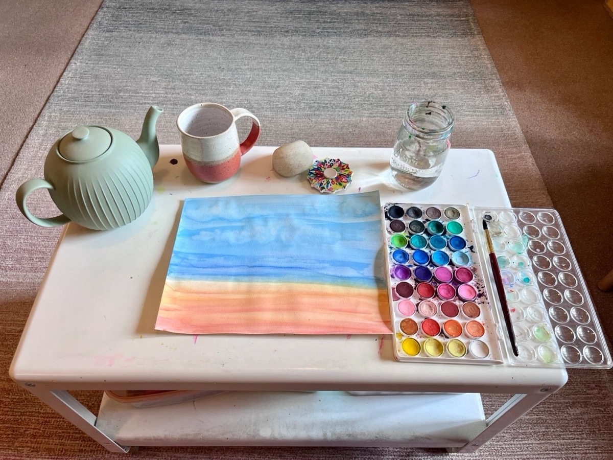 Watercolor painting setup with tea and brush