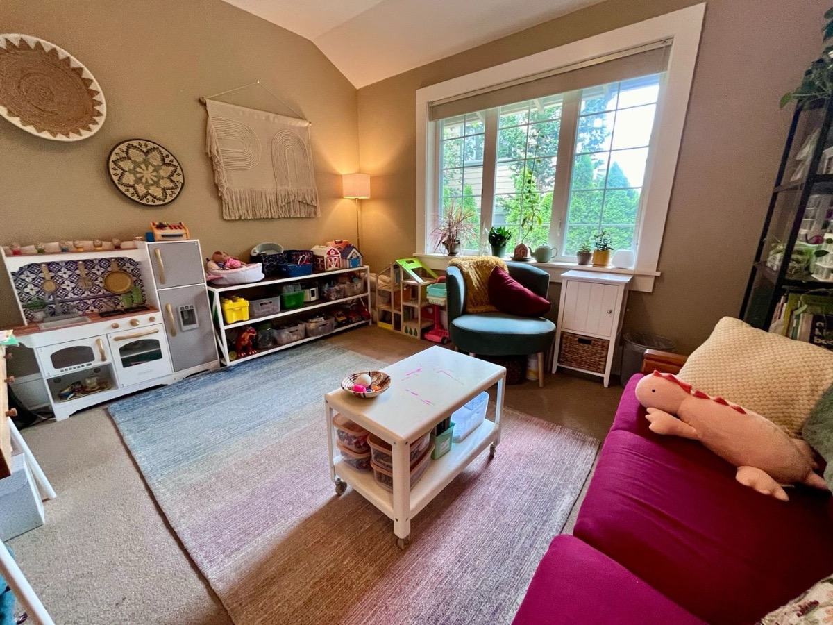 Bright playroom with a play kitchen, toy shelves, and a large window