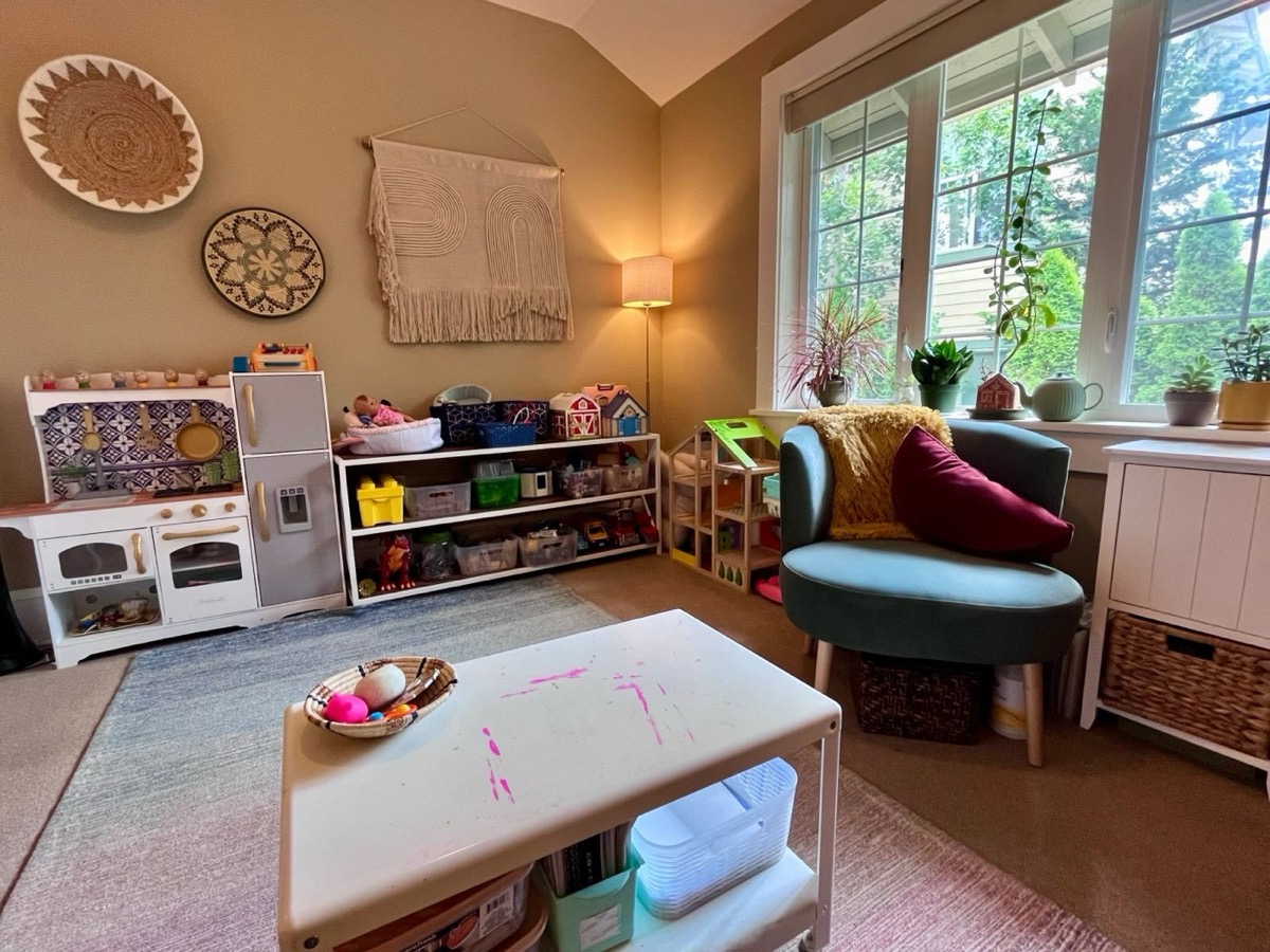 Playroom with a play kitchen, toy shelves, and a cozy armchair by the window